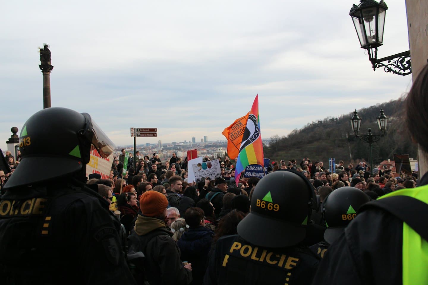 Demonstranti s transparenty a duhovou vlajkou na demonstraci s policií.