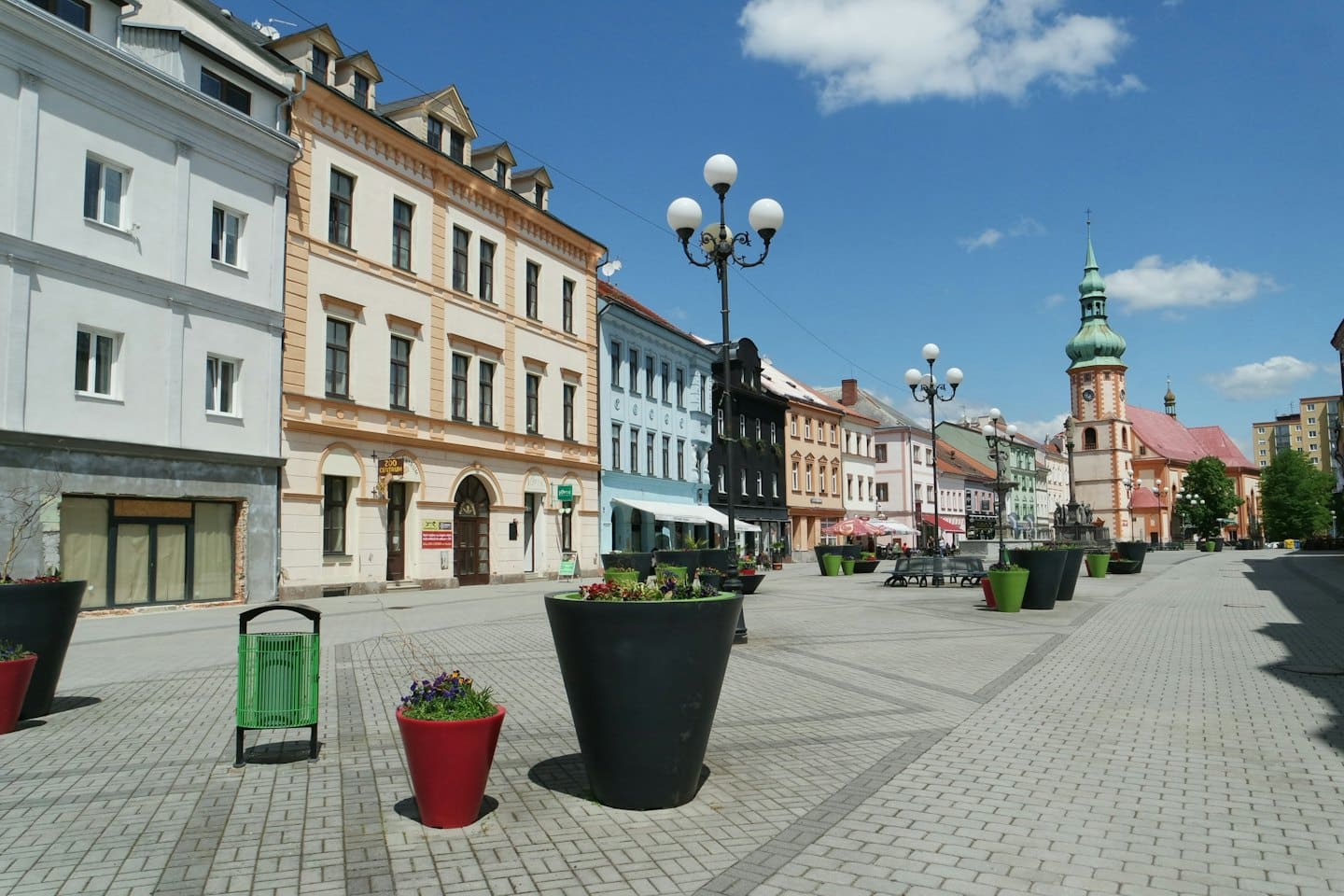 Historické náměstí s kostelem se zelenou věží.